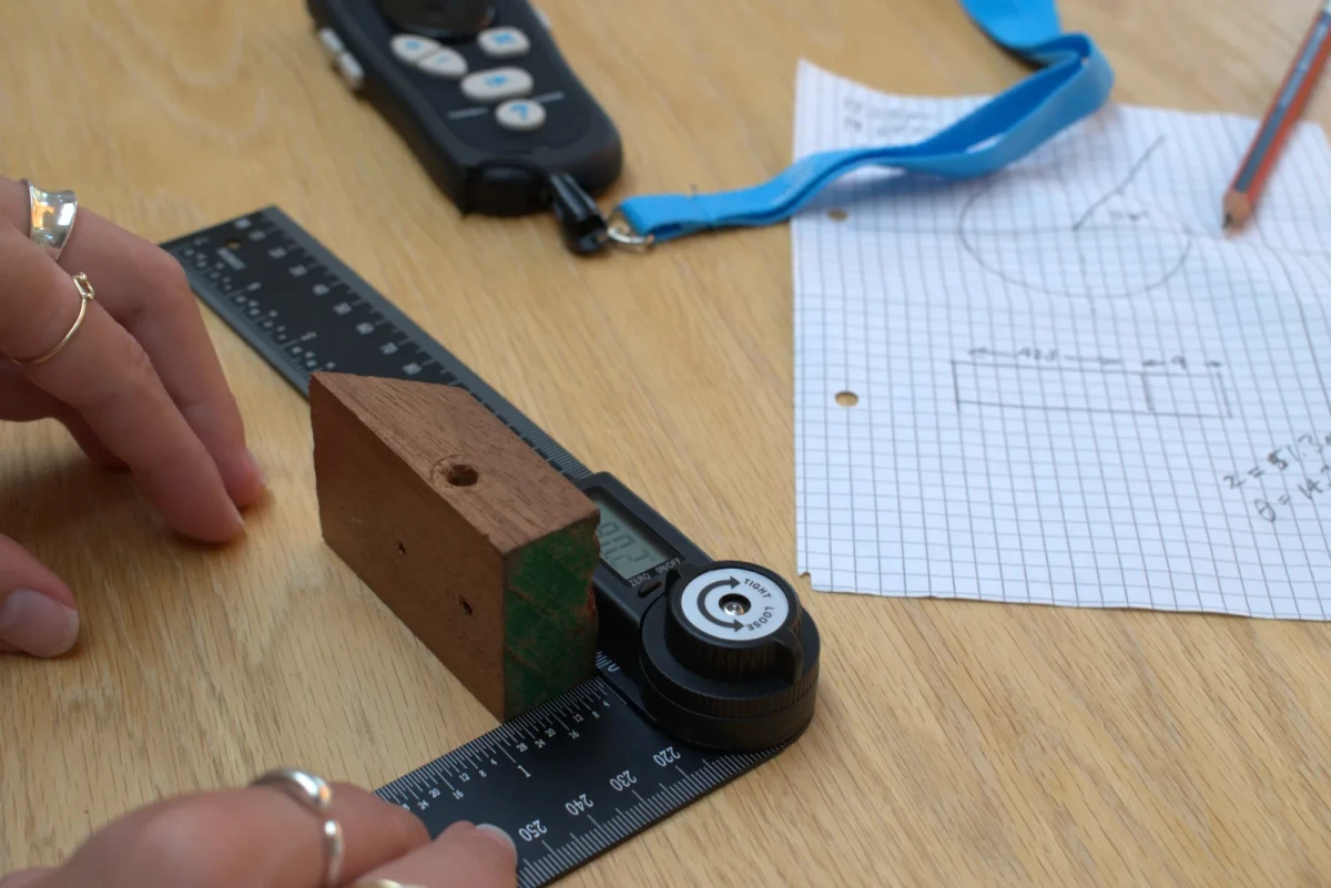 Hands checking a chamfered wooden block against the AM-1, the Controller behind
