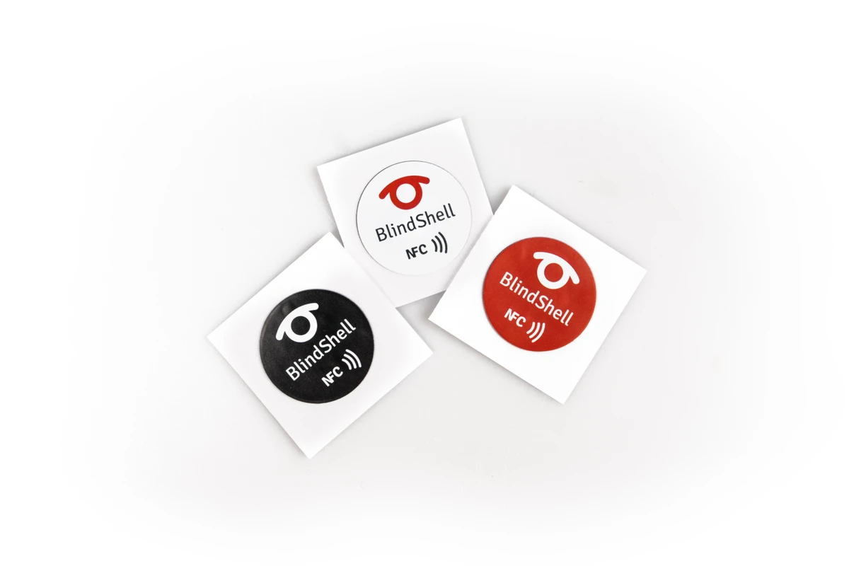 Three round BlindShell NFC tags in white, black and red-orange.