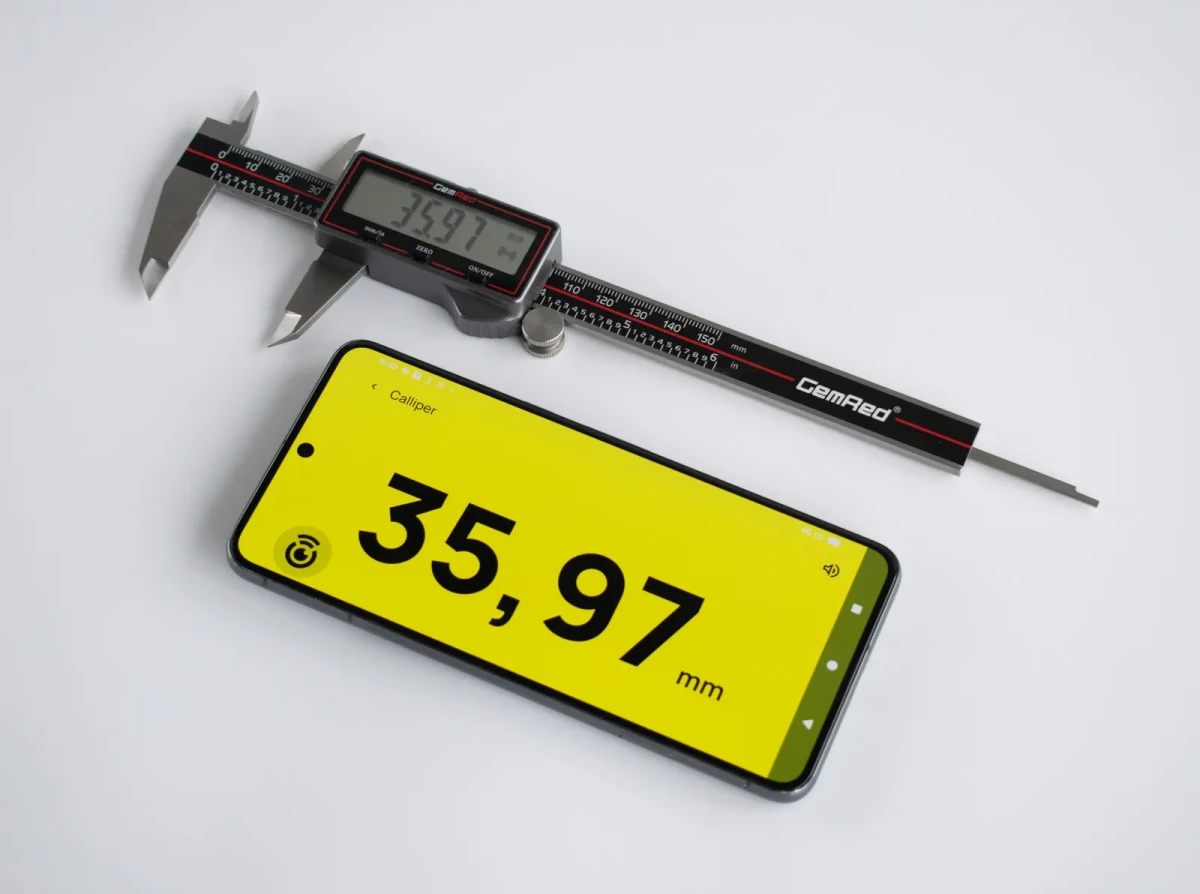 The CP-1 beside a phone showing 35,97 mm in huge black type on yellow