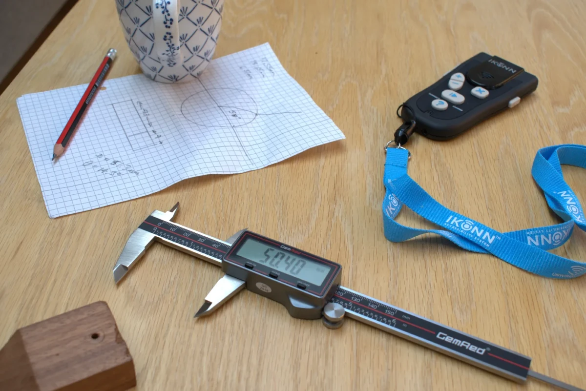 The CP-1 on a workbench with the IKONN Controller, a lanyard and a pencil sketch