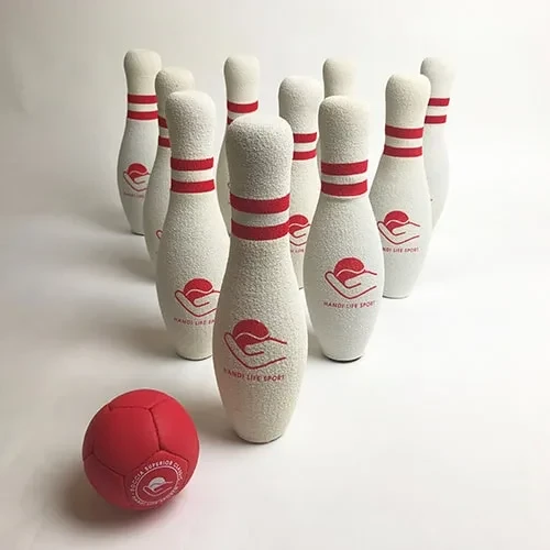 Zehn weiße Schaumstoff-Bowlingpins mit roten Streifen und ein weicher roter Ball.
