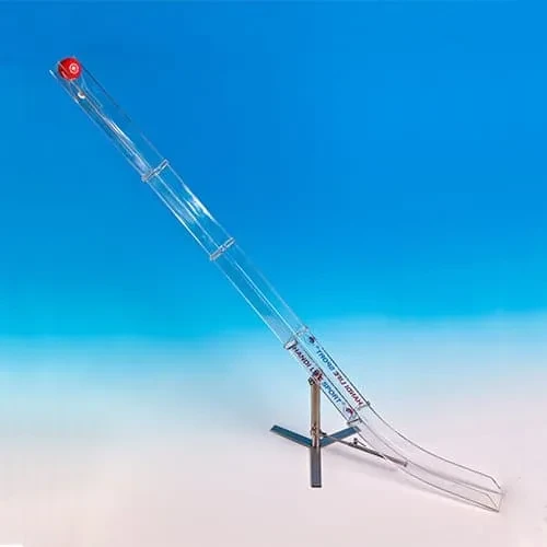 Una rampa per boccia in policarbonato trasparente su base a croce in acciaio inox, inclinata verso l'alto, con un supporto per palla rosso in cima.