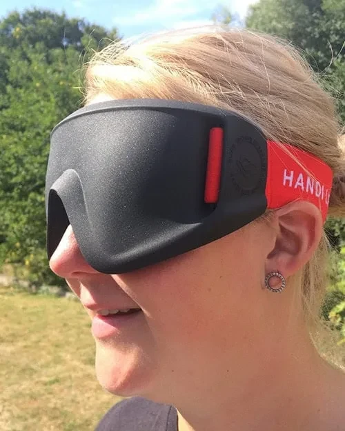 A person wearing a black moulded blind-sports eyeshade with a red strap.