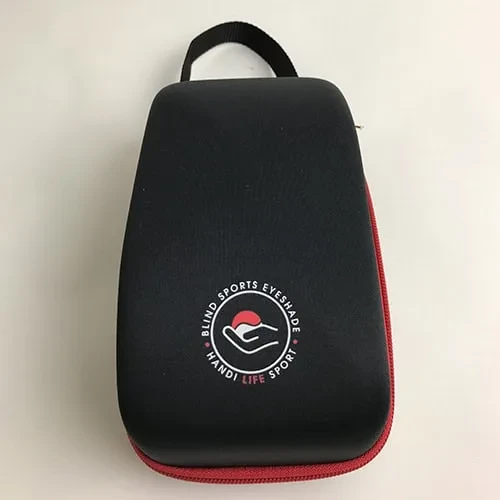 Ein schwarzes Hartschalenetui mit rotem Reißverschluss, Trageschlaufe und dem Blind Sports Eyeshade Logo.
