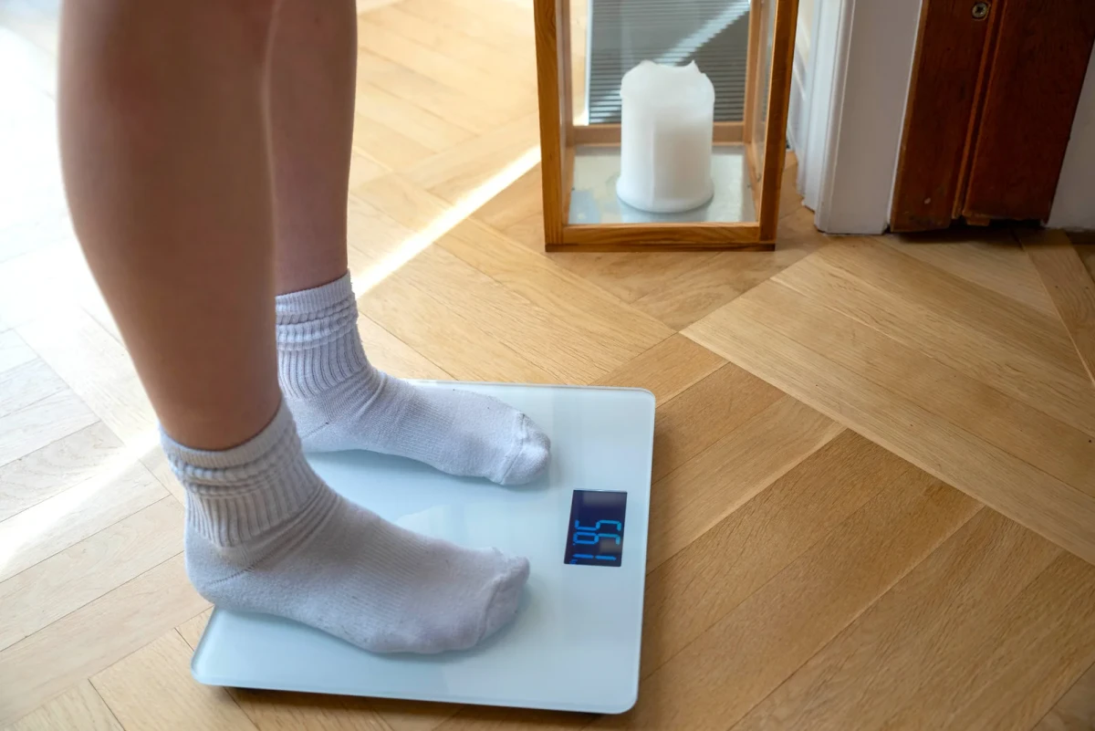 A person in white socks standing on the SB-1 on a herringbone oak floor
