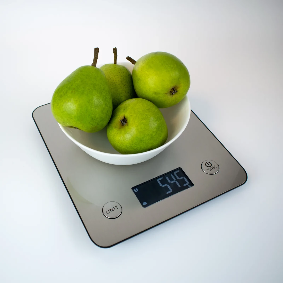 A white bowl of four green pears on the SK-1, display reading 545 grams