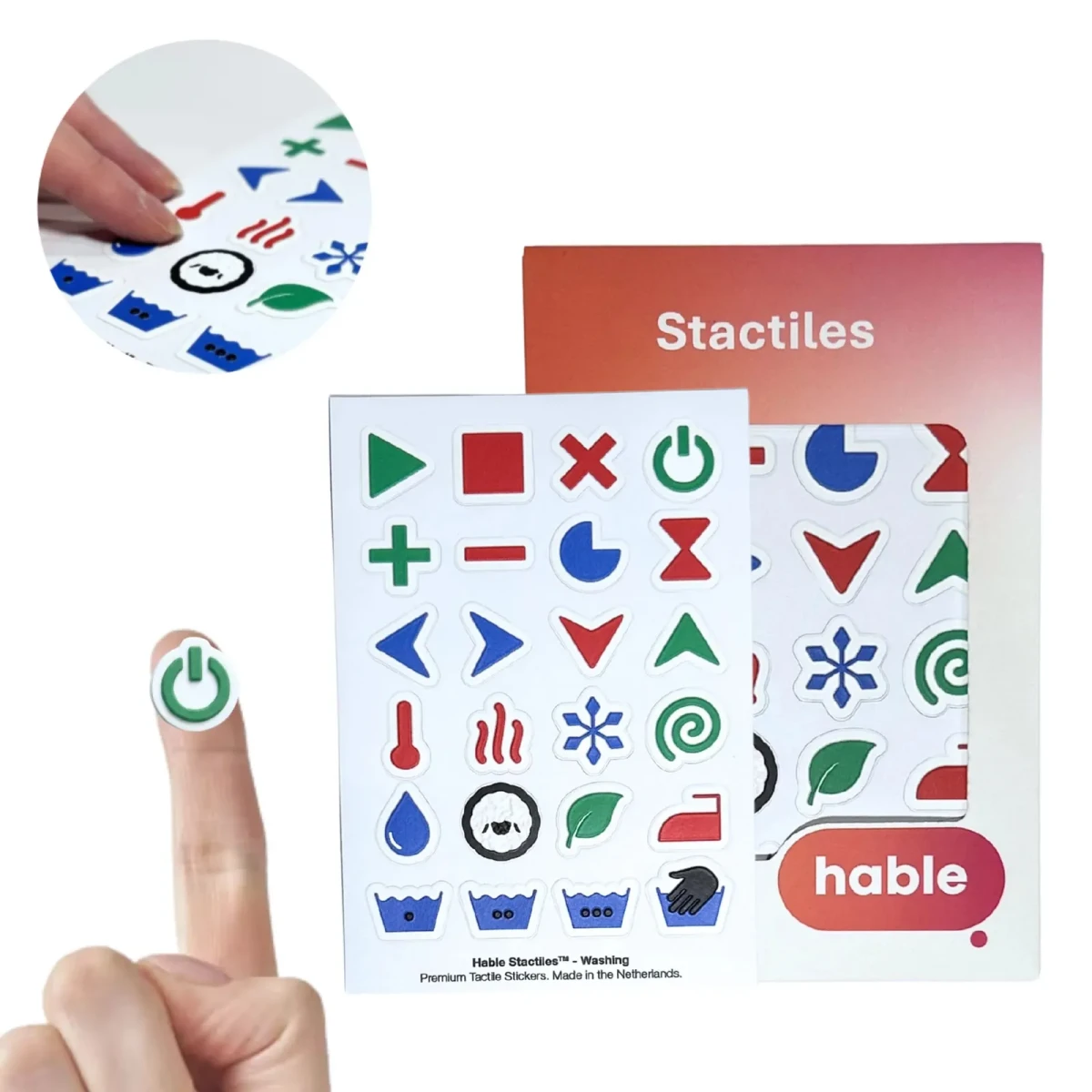 Das Hable Stactiles Waschset: Ein weißes Aufkleberblatt mit erhabenen Wäschesymbolen wie Thermometer, Hitzewellen, Schneeflocke, Wollschaf, Blatt, Bügeleisen und Waschbottich, vor der orangefarbenen Hable Verpackung. Eine Fingerspitze liegt auf einem grünen Ein-Aus-Taste Aufkleber, und eine eingefügte Nahaufnahme zeigt Finger, die die erhabenen Aufkleber ertasten.