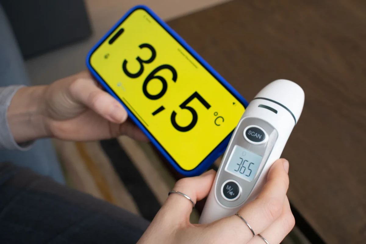 The TF-1 held beside a phone showing 36.5 Celsius in huge black figures on yellow