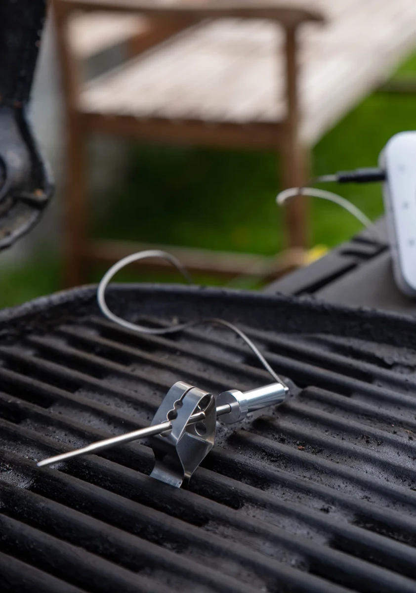 A steel probe clipped to a barbecue grate, cable running to the TK-1 on the side shelf