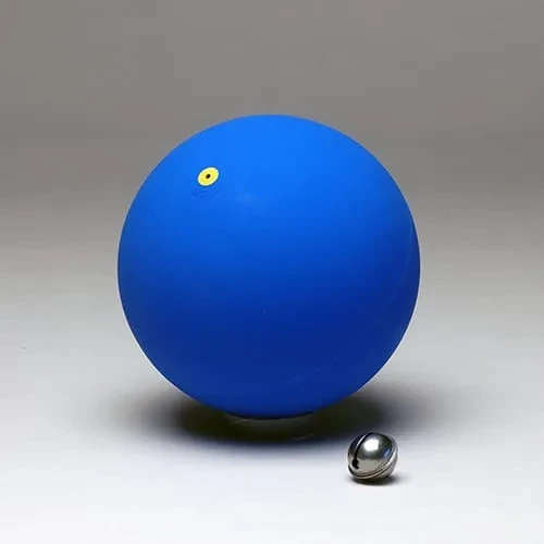 كرة مطاطية زرقاء مطفأة بقرص صمام أصفر صغير، وإلى جانبها جرس كرويّ من الكروم.